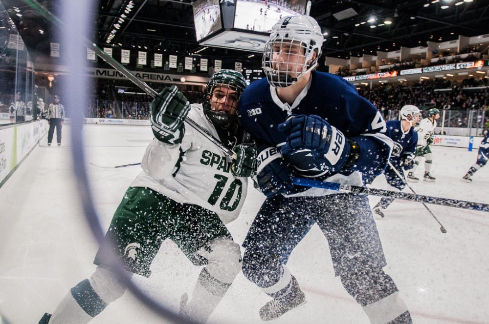 Sophomore forward Sam Saliba (10) fights for the puck with Penn State's defenseman Kris Myllari (4) during the game on Feb. 16, 2018 at Munn Ice Arena. The Spartans beat the Nittany Lions 4-2. 
