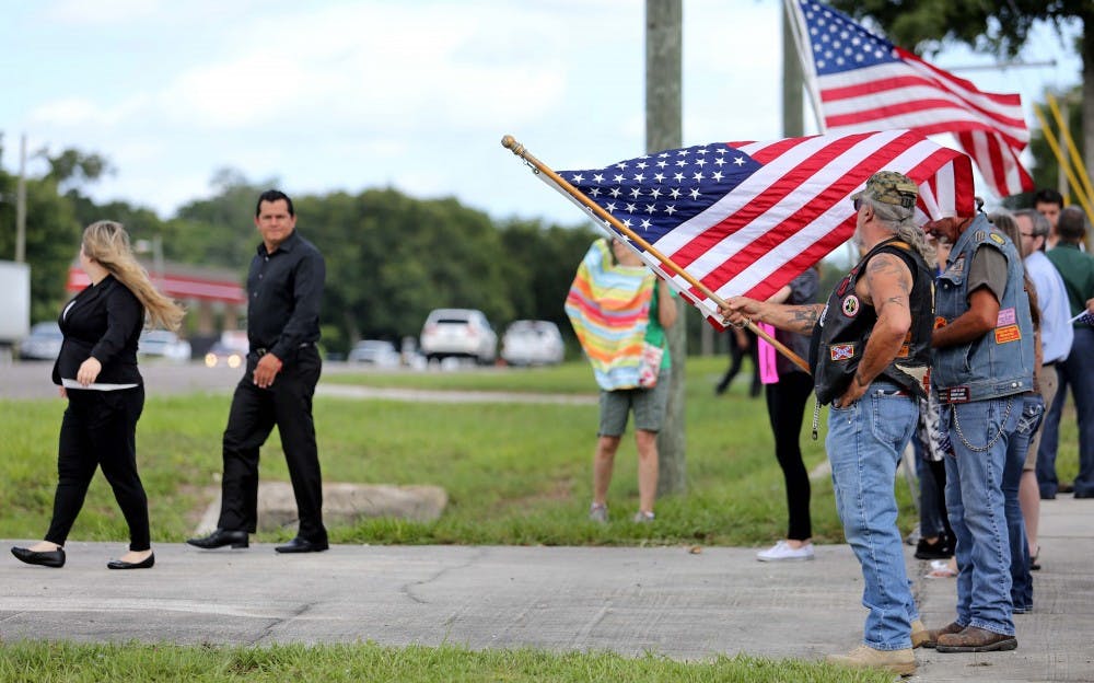 Demonstrators hold flags and signs in support of Miguel Angel Honorato as family and friends arrive at St. Francis of Assisi Catholic Church for Honorato&apos;s funeral on June 21, 2016 in Apopka, Fla., north of Orlando. Honorato was one of the 49 victims fatally wounded in the Pulse nightclub shooting. (Joe Burbank/Orlando Sentinel/TNS)
