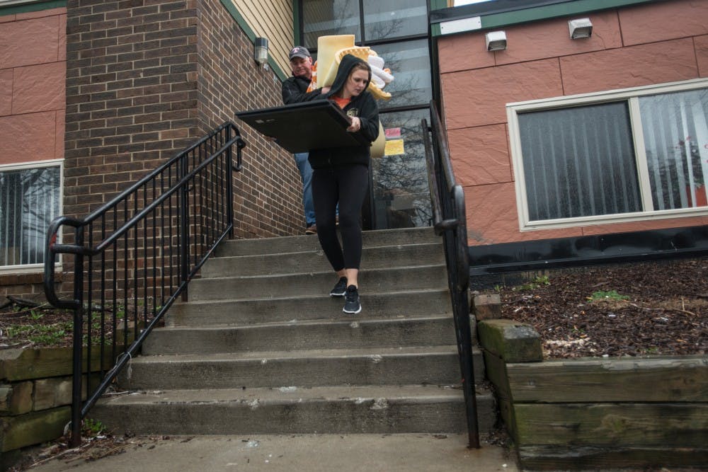 Journalism and media and information senior Anne Abendroth and her father Joel Abendroth carry furnishings from Anne's apartment on March 31, 2016 outside of Abbot Manor at 910 Abbot Road in East Lansing. The building was declared unsafe for human occupancy or use and it was deemed unlawful for any person to use or occupy the space after 4 p.m. March 30, 2016.