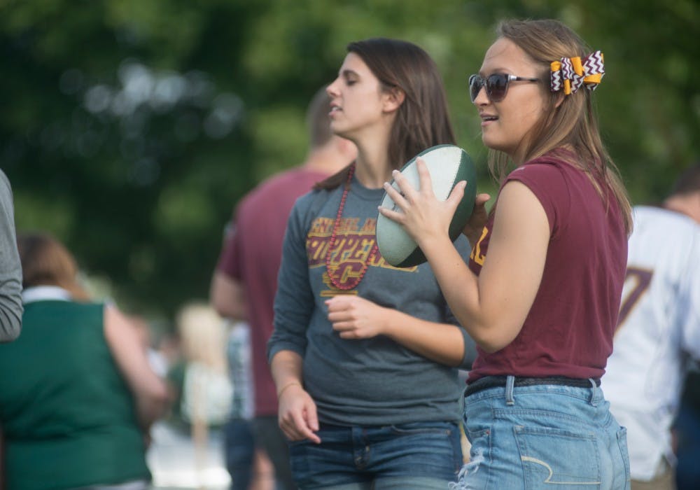 <p>Central Michigan junior Cassidy Cobb throws a football during the ASMSU tailgate prior to the game against Central Michigan on Sept. 26, 2015, at the tennis courts on Wilson Road. Spartans and Chippewas alike gathered at the tailgate to play games and listen to a DJ sponsored by ASMSU. Alice Kole/The State News</p>