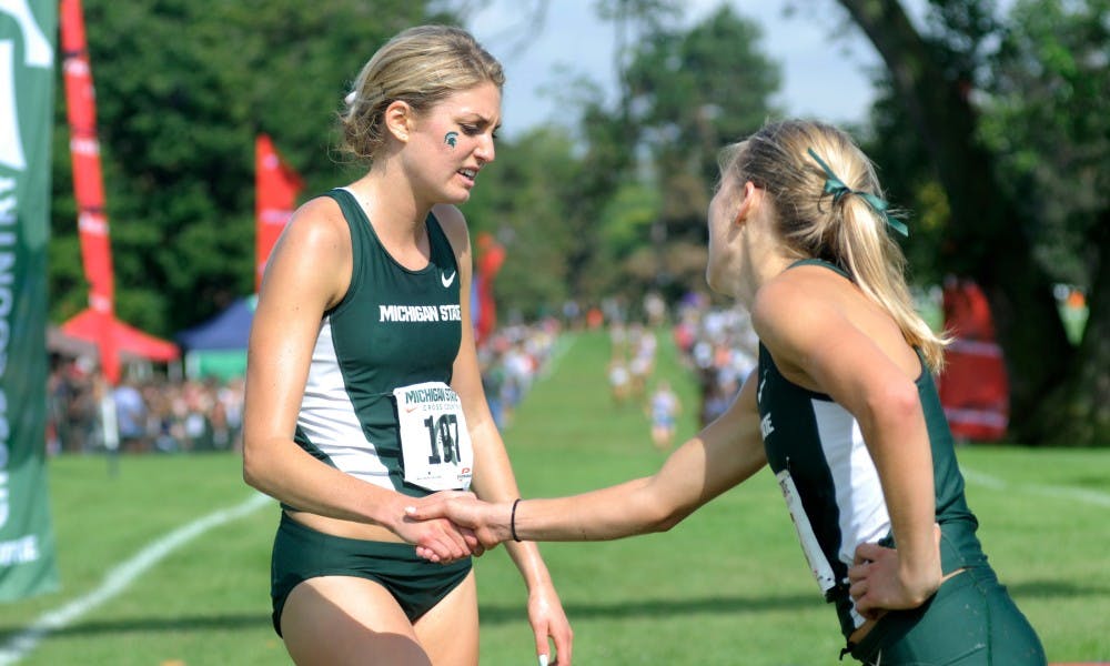 <p>Junior Rachele Schulist, left, and teammate junior Alexis Wiersma congratulate each other after the women's college 6K race Sept. 18, 2015 during the Spartan Invitational at Forest Akers Golf Course in East Lansing. Schulist's time for this race was 21:01. Wiersma's time was 21:07.</p>