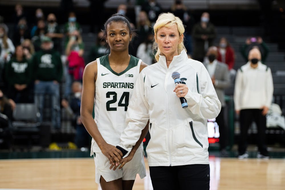 <p>Senior guard Nia Clouden (24) stands with MSU head women's basketball coach Suzy Merchant as the two recount her college career. The Spartans held a ceremony honoring the four graduating seniors of the women's basketball team at the Breslin Center on Feb. 27, 2022.</p>