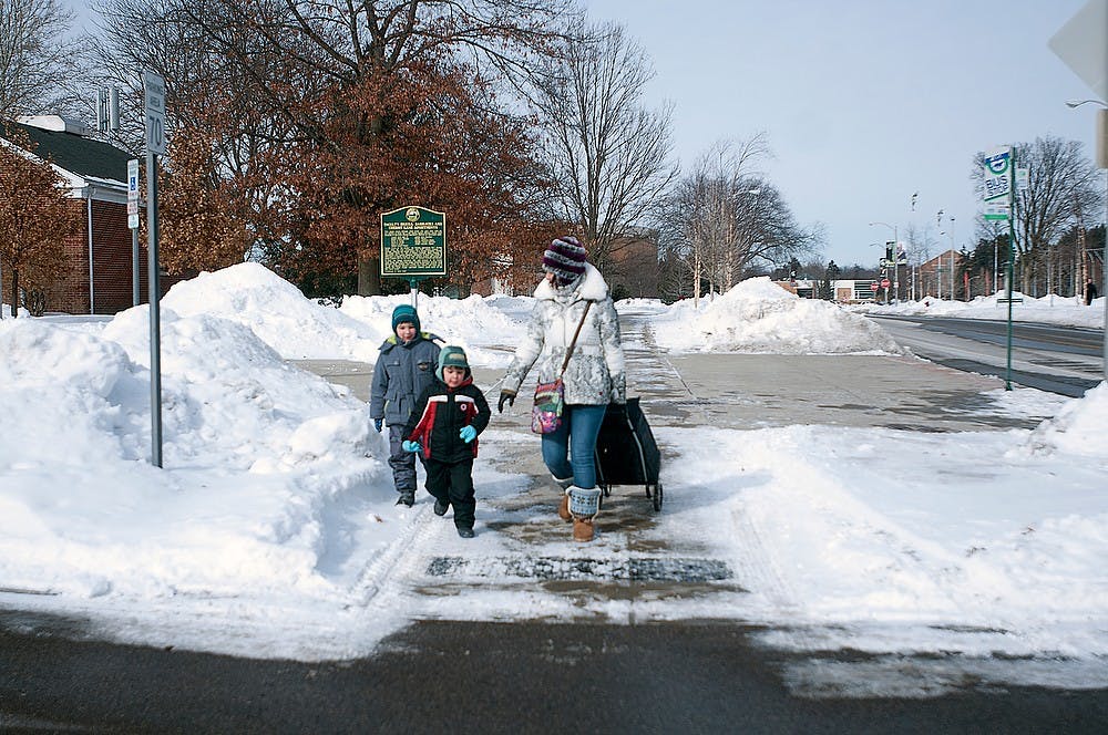 <p>Anastasia Tolstora walks with her children Yury and Victor Feb. 16, 2015, outside Wonders Hall. Kelsey Feldpausch/The State News</p>