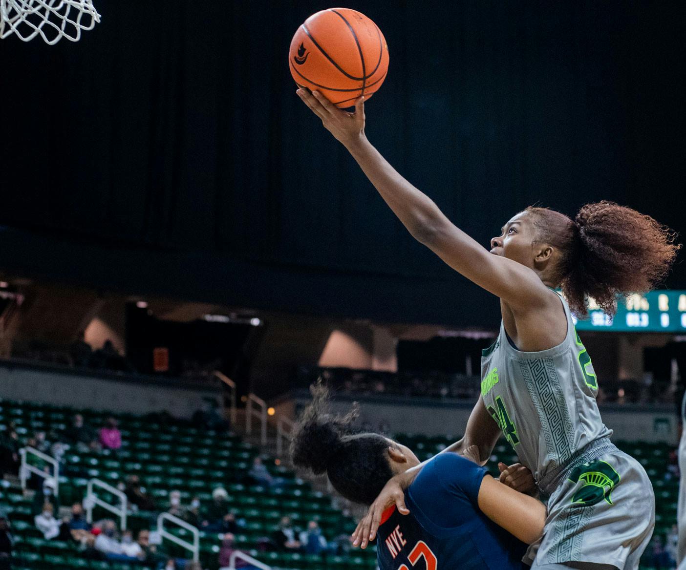 <p>Senior guard Nia Clouden (24) leaps over Illinois&#x27;s sophomore guard Aaliyah Nye to score during the second quarter of the game. The Spartans beat the Fighting Illini, 75-60, in their Big Ten opener on Dec. 9, 2021.</p>