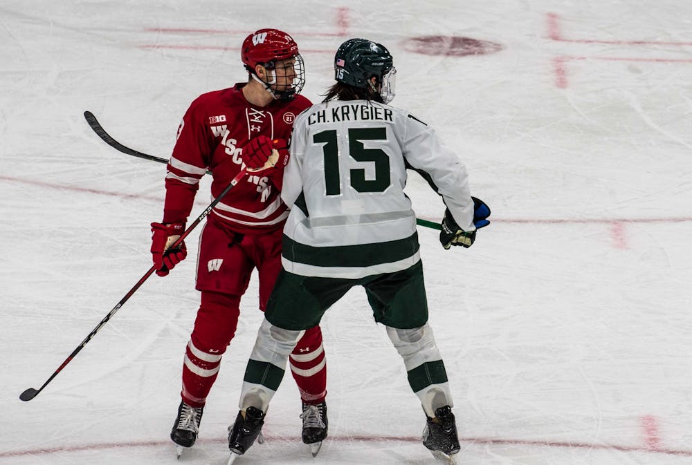 <p>Senior defender Christian Krygier (15) watches as Wisconsin attempts to score a goal during the third period while guarding another player. The Badgers shut out the Spartans 4-0 at Munn Ice Arena on March 5, 2021. </p>