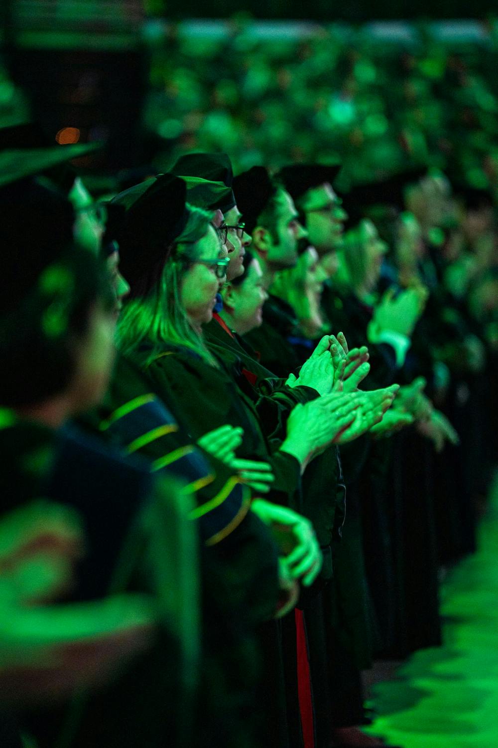 MSU professors applaud MSU president Kevin Guskiewicz as he takes the stage during the fall 2024 commencement ceremony at the Breslin Center on Dec. 14, 2024.