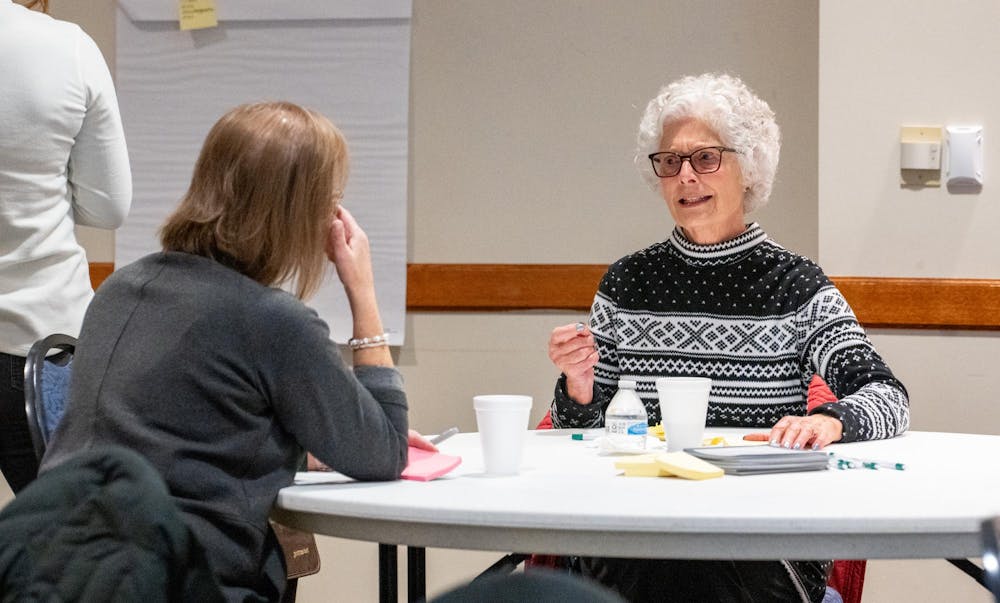 A community member speaks with someone who helped facilitate the MSU Extension’s East Lansing public listening session at the Hannah Community Center on Nov. 29, 2023. 