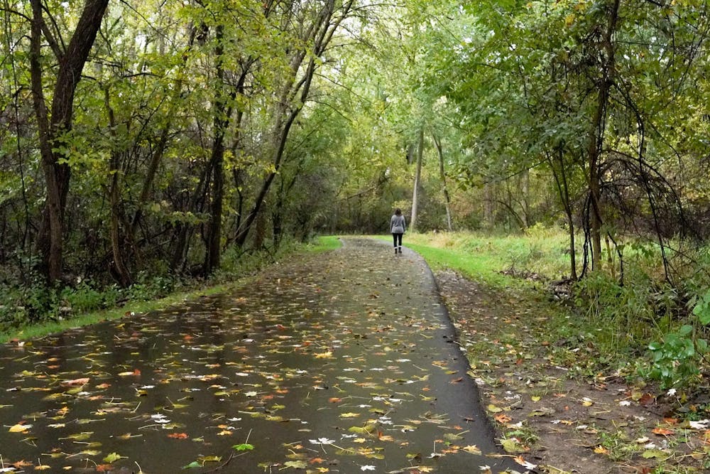 A woman walking on a paved trail at Azaadiika Park in East Lansing, Michigan on Oct. 14, 2023.