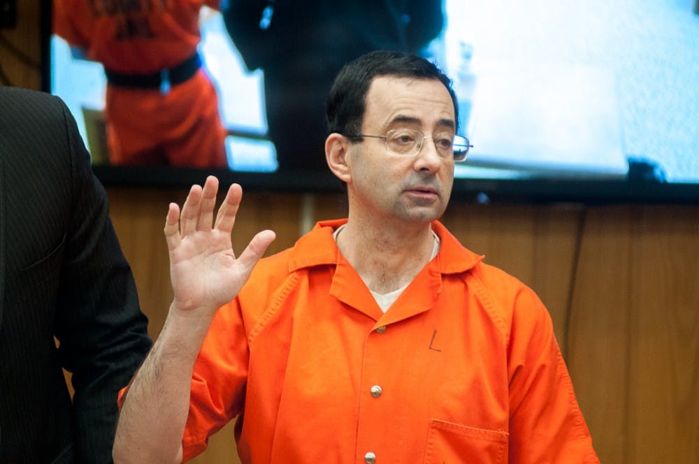 Ex-MSU physician Larry Nassar raises his right hand before reading a statement on the third and final day of sentencing on Feb. 5, 2018 in the Eaton County courtroom. Nassar faced three counts of criminal sexual conduct in Eaton County and was sentenced up to 125 years.
