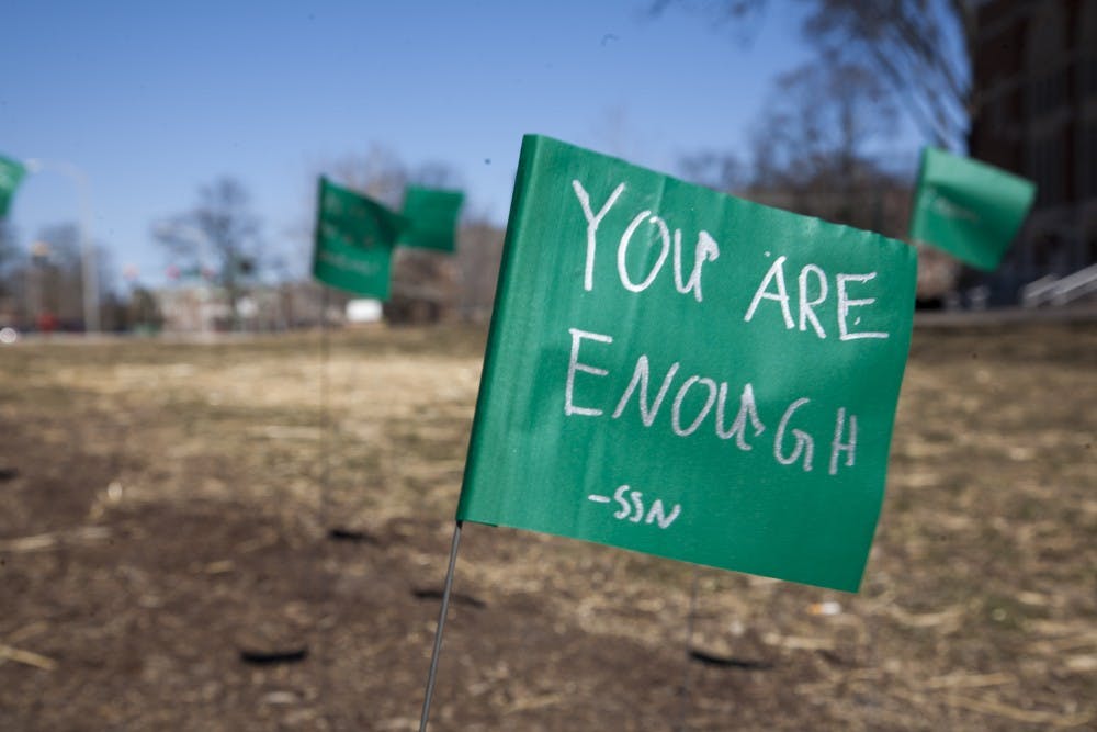 <p>Green flags with motivational messages written by students as part of the Green Flag Challenge on March 19, 2018, at The Rock on Farm Lane. (Charles Benoit | State News)</p>