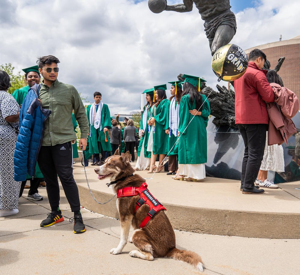<p>A service dog with a balloon sits outside Breslin Center surrounded by graduating Michigan State students taking pictures in East Lansing, Mich., on May 1, 2026.</p>