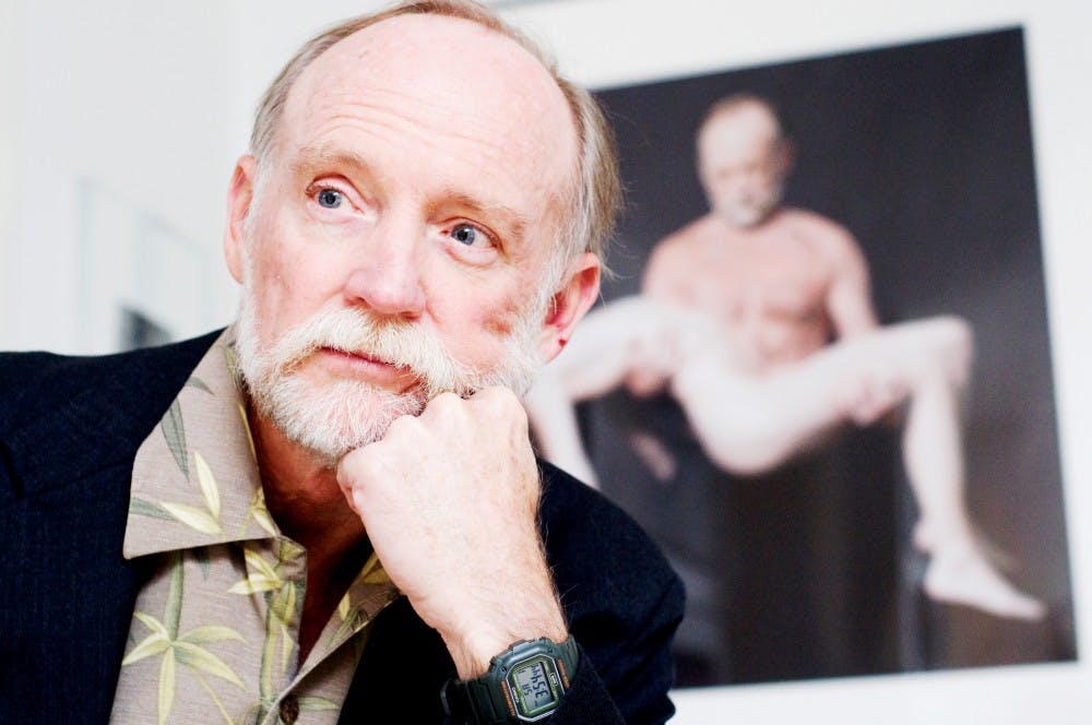 MSU Department of Art and Art History professor Danny Guthrie poses in front one of his photographs which hangs on the wall of his bedroom. Justin Wan/The State News