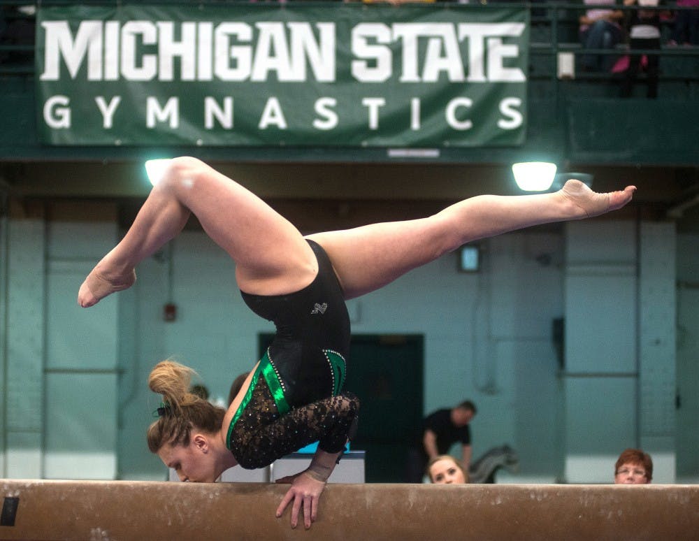 <p>Freshman Victoria Heuhn performs a dance pose on Feb. 13, 2015, during her beam event at the women's gymnastics meet against Michigan. Michigan scored a 49.3000 on beam beating Michigan State's score of 48.300. Emily Nagle/The State News</p>