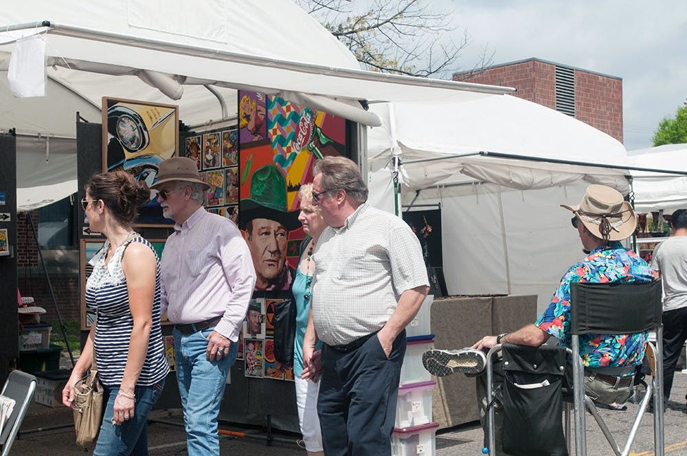 <p>Festival goers glance at art work  May 17, 2015 at the East Lansing Art Festival. Asha Johnson/The State News</p>