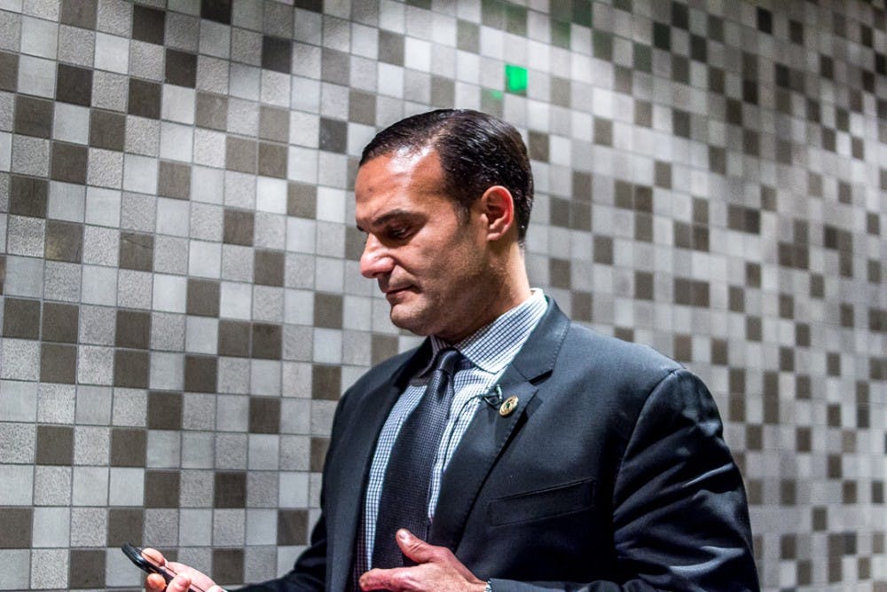 <p>Board member Brian Mosallam checks his phone before the town meeting on Feb. 1, 2018 at Kellogg Center. The town hall brought together students, staff and members of the MSU community to discuss the current climate of the campus.&nbsp;</p>