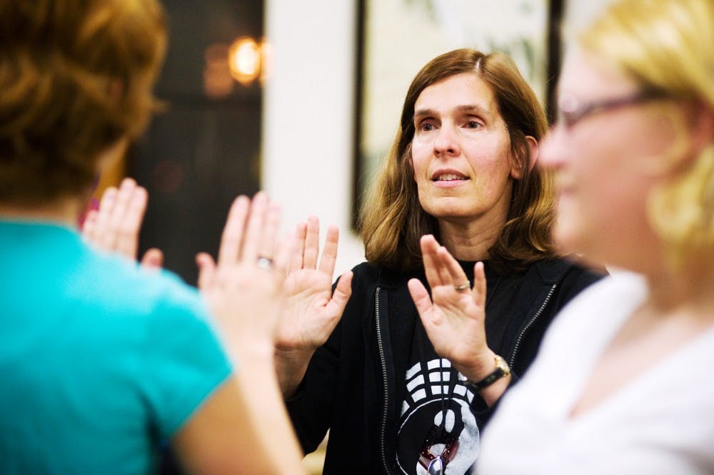 Wanderer's Teahouse owner Elizabeth Marazita tells partners to feel each other's energies during a Tai Chi event hosted Tuesday night by the Interfaith Council in Campbell Hall. Lauren Wood/The State News