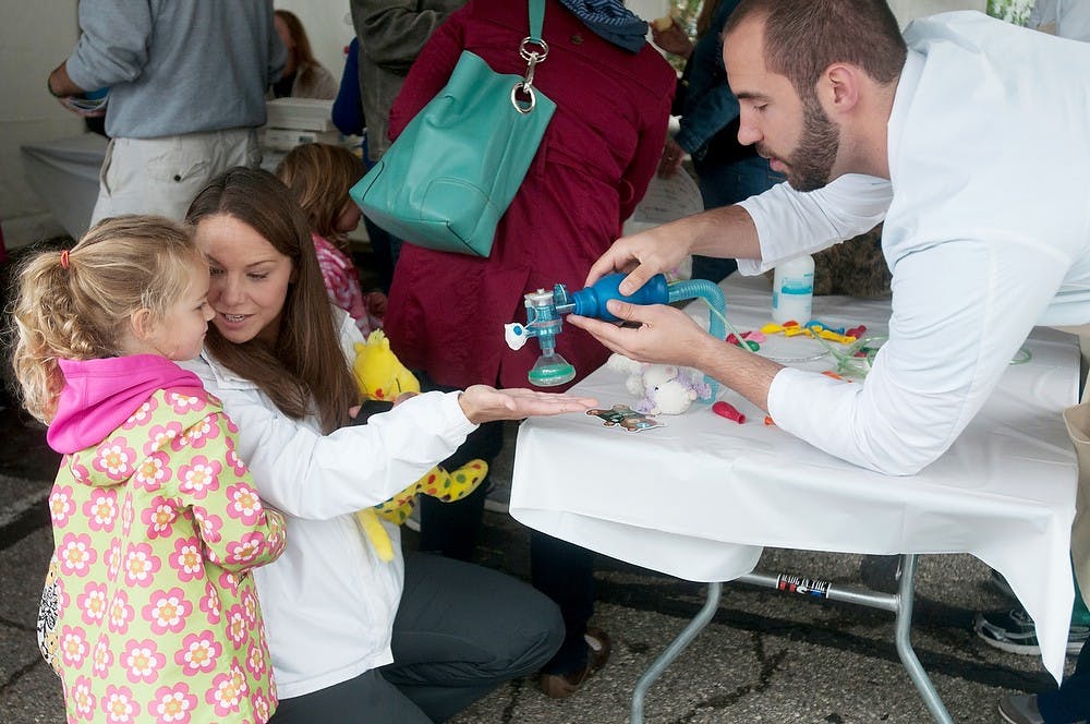 <p>Okemos, Mich., resident Kristen Degan and her daughter Kira Degan, 3, go to the Teddy Bear Hospital to get treated by volunteer Ethan Ruland on Sept. 13, 2014, at the Michigan 4-H Children's Garden in East Lansing, Mich. Aerika Williams/The State News</p>