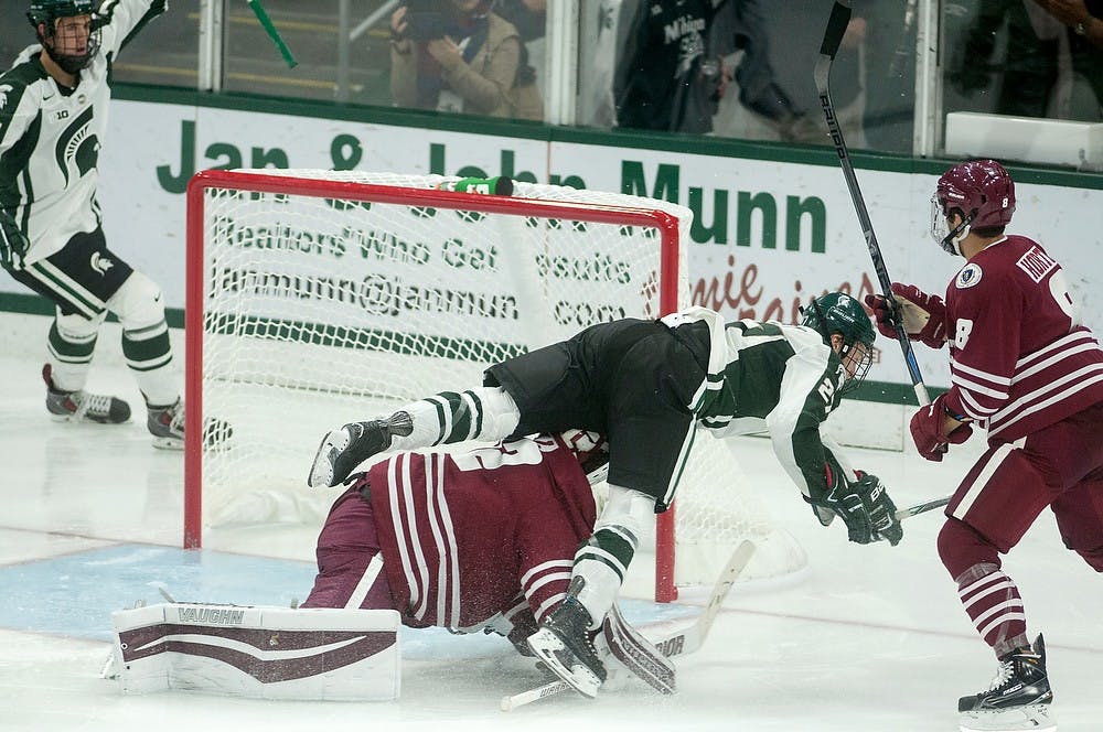 <p>Senior forward Matt Berry collides with Massachusetts goalie Henry Dill on Oct. 18, 2014, at Munn Ice Arena. The Minutemen defeated the Spartans, 4-3. Aerika Williams/The State News</p>