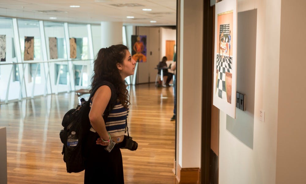 <p>Arts and humanities junior Emily Elconin views a piece of art on Oct. 12, 2015 at the Lookout! Gallery in Snyder hall. The gallery is currently featuring "Living Inside the World: Artwork from Michigan's Prisons" which will run until October 23, 2015. </p>