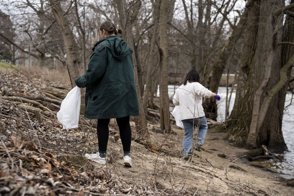 <p>Fisheries and wildlife majors Kelly Baltusis and Sharon An are both members of the FW Club picking up trash in the Red Cedar River during the river cleanup on April 9, 2022.</p>