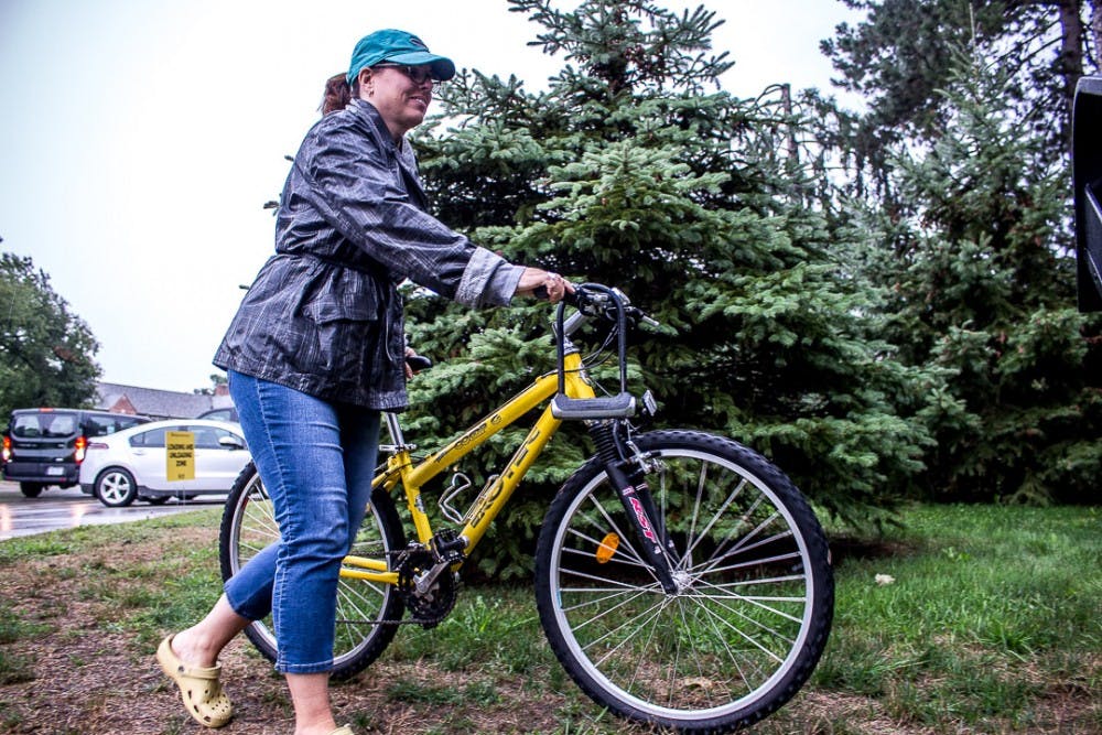 <p>Kalamazoo resident Joy Hess moves a bike on Aug. 26, 2018 in front of Williams Hall. Thousands of first-year students moved onto campus during the university’s official move-in day.</p>