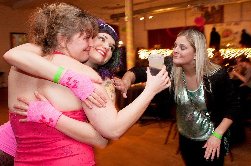 	<p>Lansing Derby Vixens Kathryn Meninga also known as Irish Justice, left, and Katie Corr also known as Psycho Hose Beast, middle, embrace as friend and Mount Pleasant resident Jessica Salisburg, right, watches during the Skatie Hawkins Dance on Feb. 23, 2013, at the Loft in Lansing. Natalie Kolb/The State News </p>