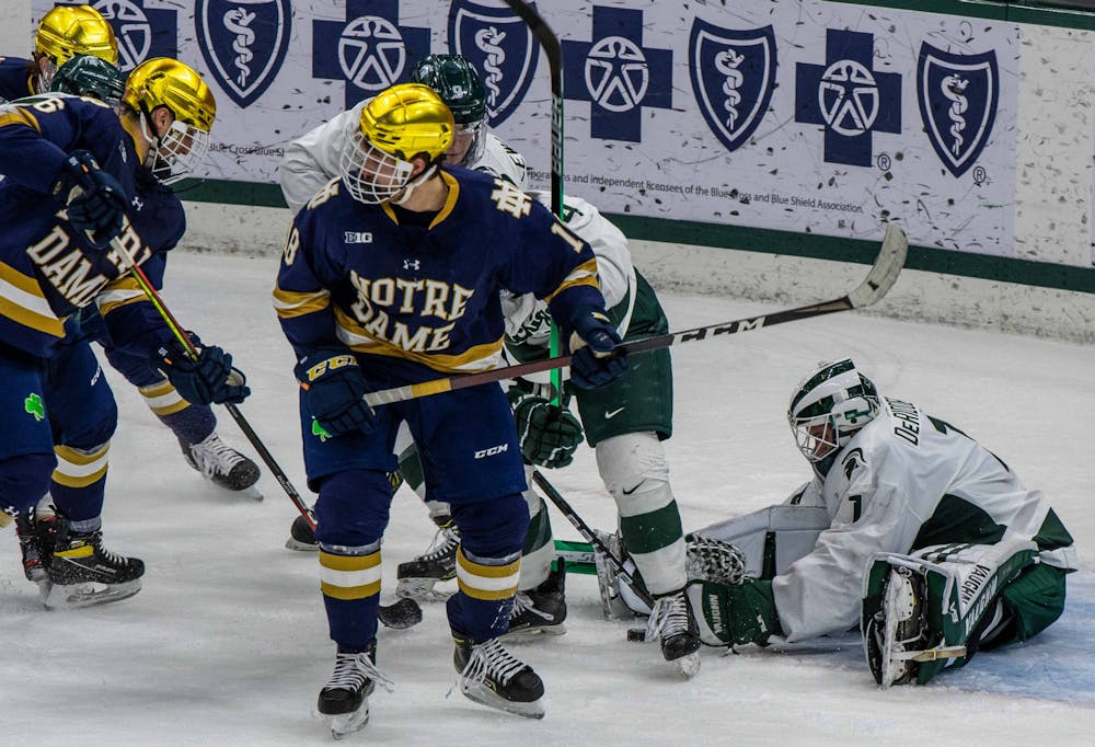 DeRidder reaches for the fallen puck in the second period while Notre Dame tries to score. The Fighting Irish shutout the Spartans 2-0 on Feb. 27, 2021.