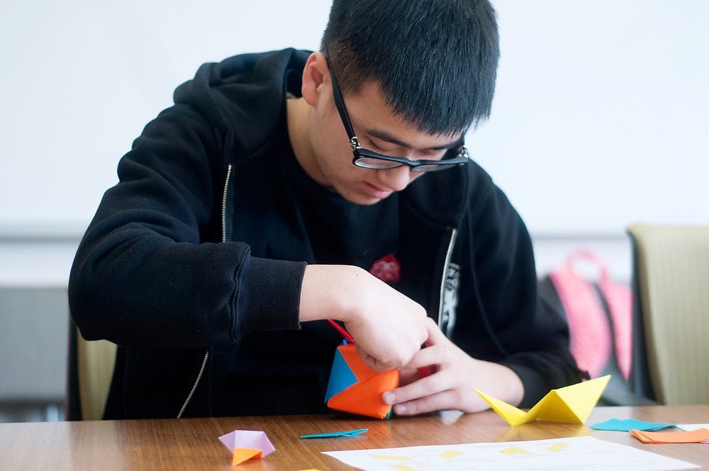 <p>Supply chain management sophomore Huanchen Lu folds origami on March 18, 2014, at Wells Hall. He heard about the event in his Japanese culture class when his professor announced it. Betsy Agosta/The State News</p>