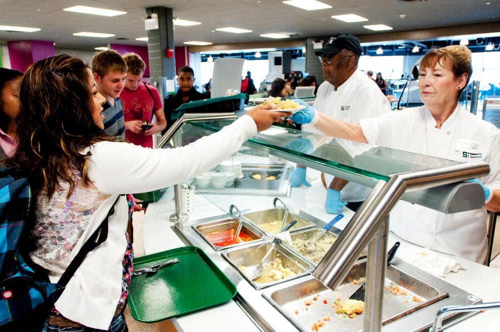 Food service worker Diane Wiseman, left, serves up lunch to criminal justice sophomore Elizabeth Sanchez on Tuesday afternoon in the Holden Hall cafeteria. The cafeteria underwent recent renovations this summer adding four new food stations. Josh Radtke/The State News