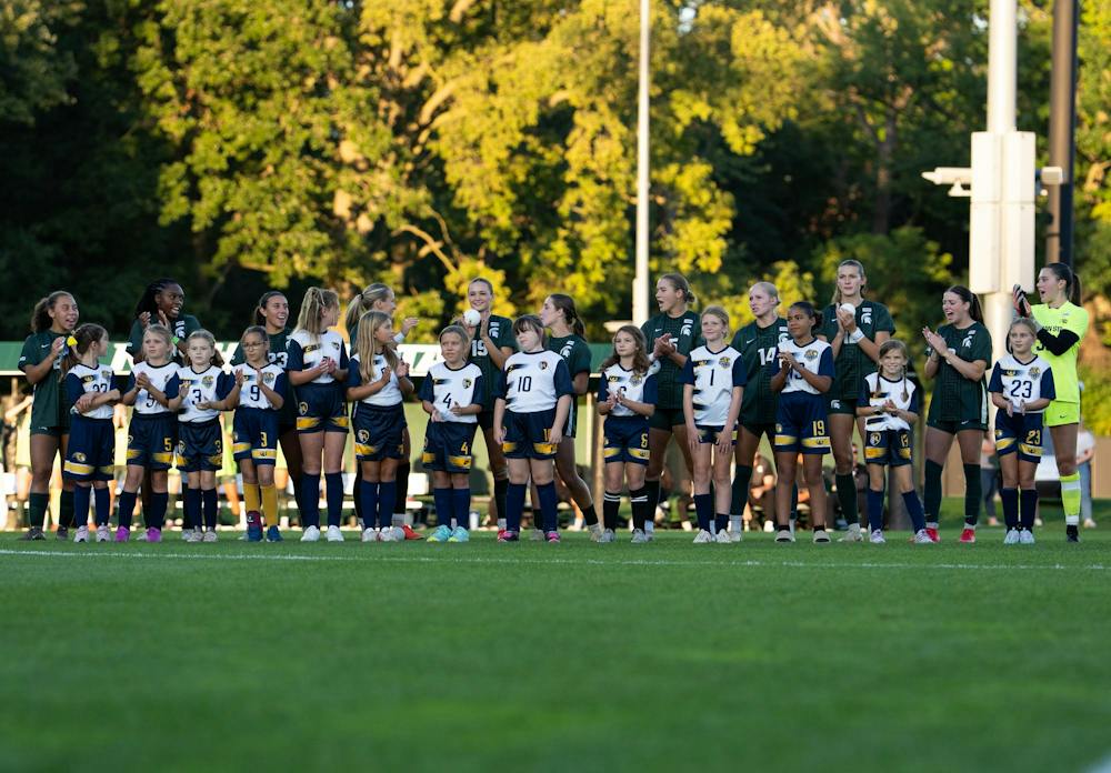 <p>The Michigan State starting lineup stands with the girls U10 Grand Ledge team at center field during the start of the game against Nebraska at DeMartin Stadium in East Lansing, Mich., on Thursday, Sept. 24, 2026.</p>