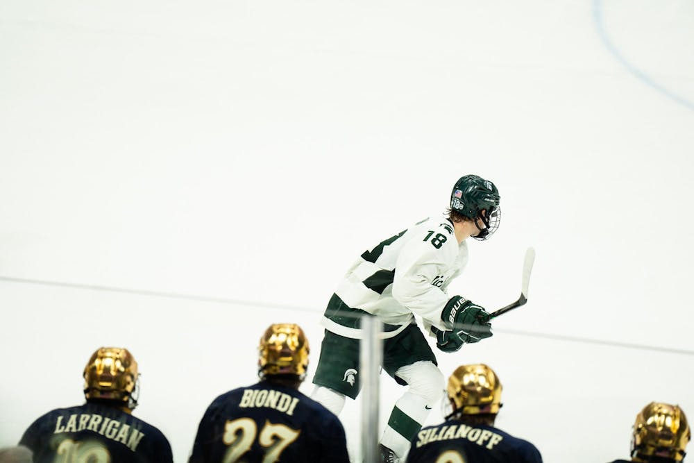 Michigan State junior right wing Joey Larson (18) skates past the Notre Dame bench at Munn Ice Arena on March 15, 2025. The Spartans took a 1-0 victory over the Fighting Irish, advancing to the Big Ten Championship.