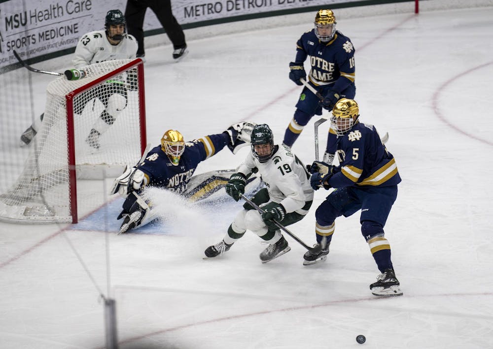 Michigan State University freshman forward Mikey DeAngelo (19) and Notre Dame junior defenseman Axel Kumlin (5) race to the puck during the MSU vs. Notre Dame men’s hockey game on Nov. 16, 2024. 