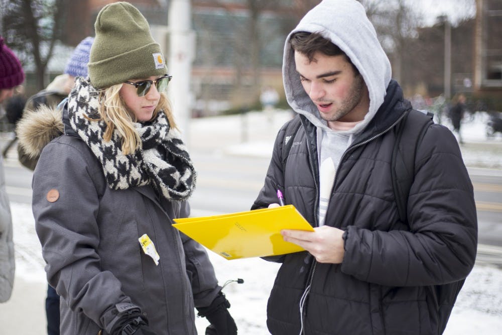 From left, Earth Science junior Hannah MacDonald watches as undecided sophomore John Jones signs petition on Feb. 9, 2017 at The Rock. The Spartan Sierra club is petitioning  to support the decommissioning of Line 5 in the Great Lakes. This is an oil pipeline that could potentially lead to safety issues in the Great Lakes. 