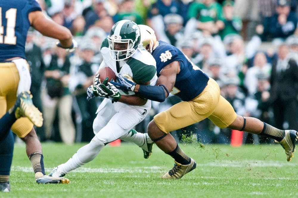 	<p>Sophomore wide receiver Macgarrett Kings Jr. tries to run the ball as Notre Dame safety Elijah Shumate wraps him up, Sept. 21, 2013, at Notre Dame Stadium. The Spartans fell to the Irish, 17-13. Khoa Nguyen/ The State News</p>