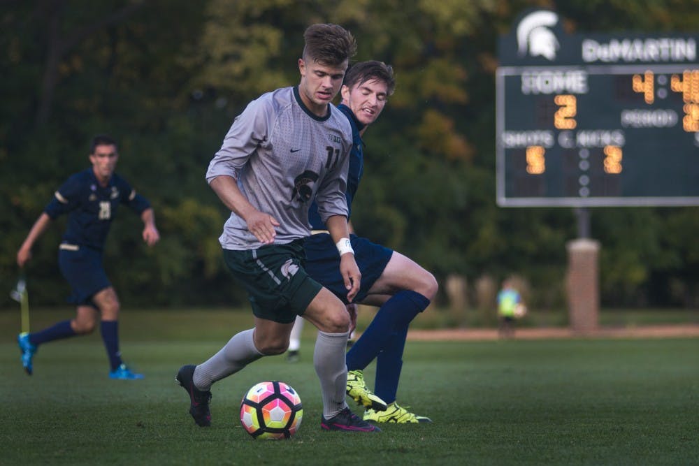 Sophomore forward Ryan Sierakowski (11) dribbles the ball past Akron defense Danilo Radjen (5) during the second half of the game against Akron on Oct. 11, 2016 at DeMartin Stadium at Old College Field. The Spartans defeated the Zips, 2-1.