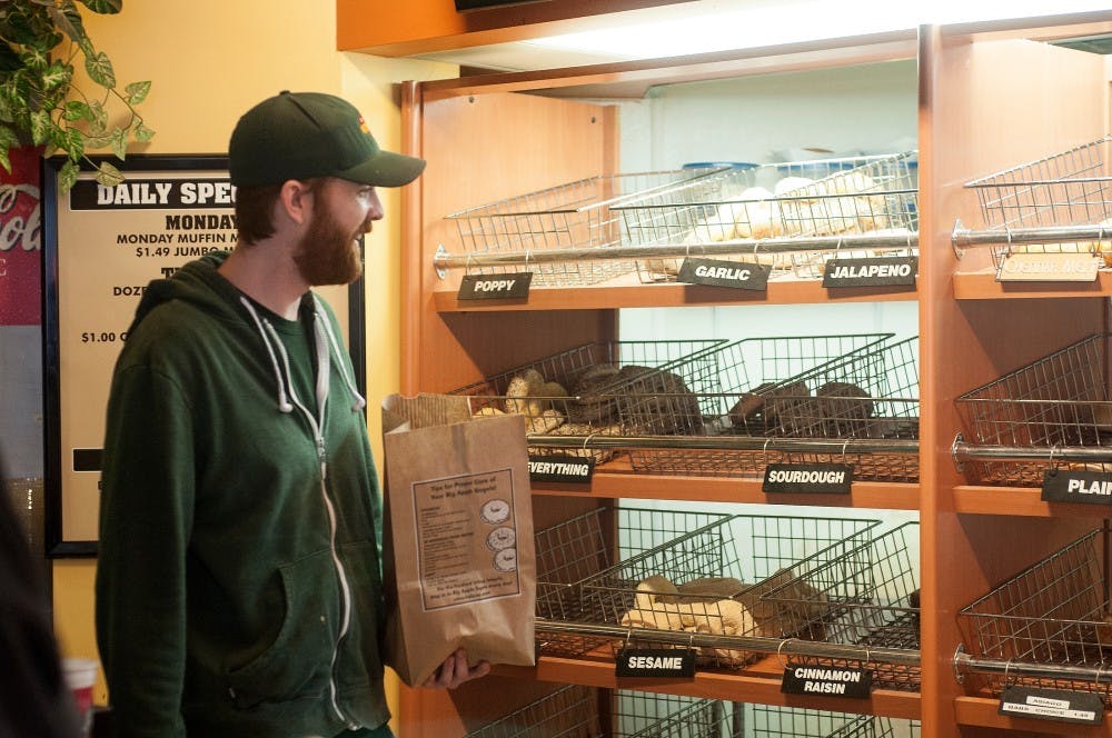 <p>MSU alumnus and East Lansing resident Matt Spizarny helps a customer decide what kind of bagels to buy April 2, 2015, at Big Apple Bagels, 248 E. Saginaw St. in East Lansing. Allyson Telgenhof/The State News.</p>