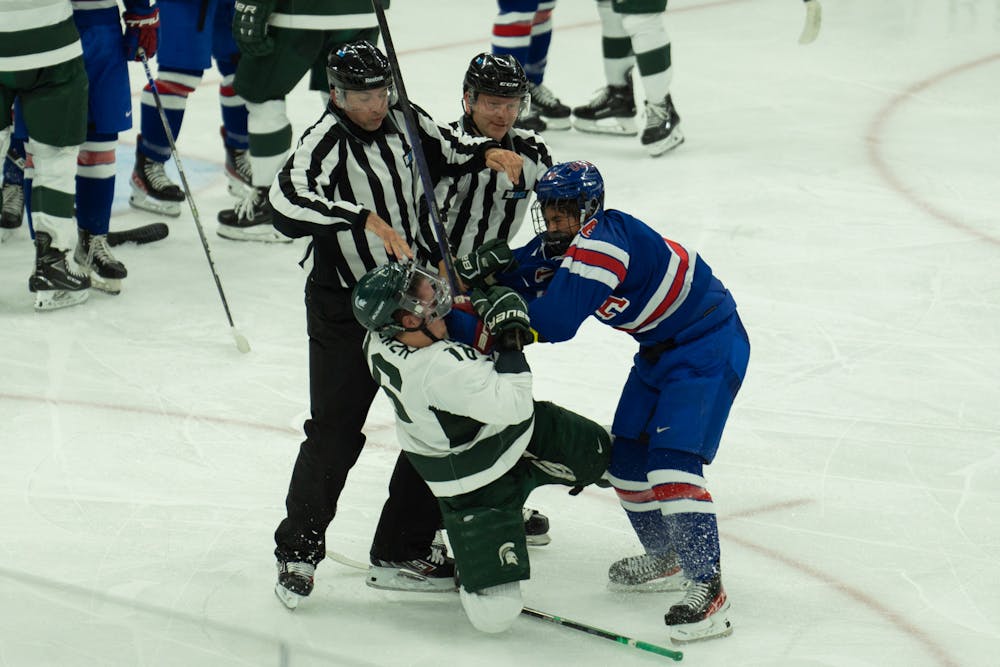 <p>Sophomore center Jesse Tucker (16) fights with a member of the USNTDP at Munn Ice Arena on Oct. 1, 2022. The Spartans lost to the USNTDP 4-3.</p>