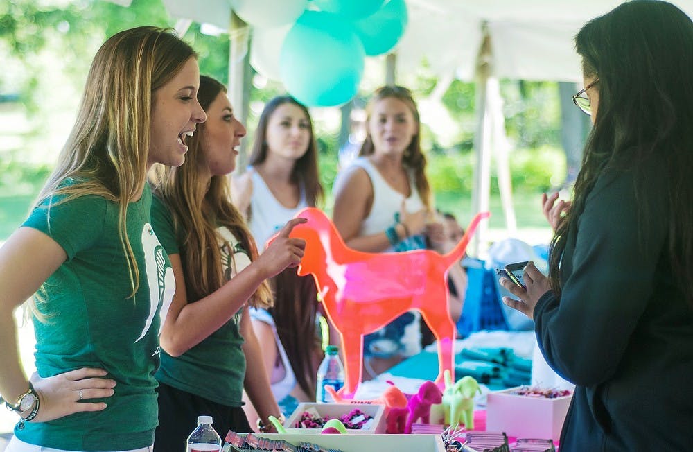 <p>Advertising senior Maddie Nichols works a booth during the Greek community welcome BBQ on Aug. 28, 2014, at the Rock on Farm Lane.  Nichols is part of the Chi Omega Sorority. Jessalyn Tamez/The State News. </p>