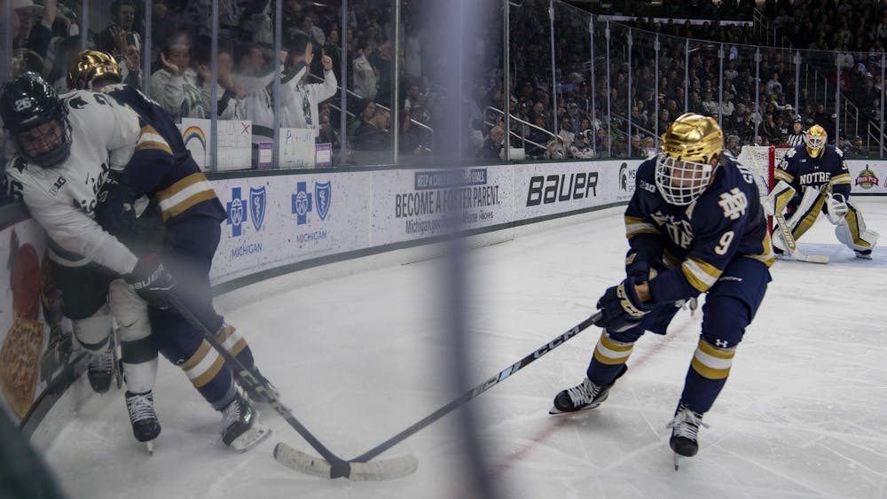 <p>A Notre Dame player pins MSU senior forward Tanner Kelly (26) to the boards at Munn Ice Arena on Nov. 15, 2024. Michigan State took the win 8-3.</p>