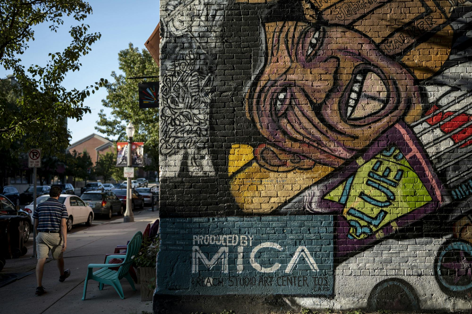 <p>A person walks past a mural in Old Town in Lansing on Sept. 8, 2022.&nbsp;</p>