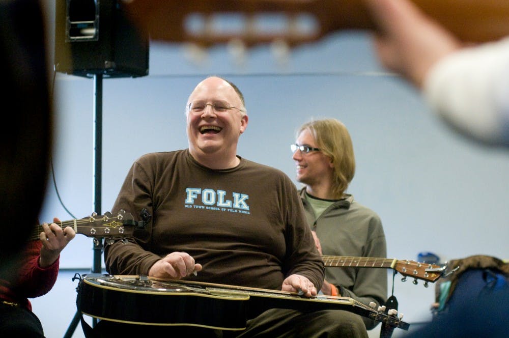 Chicago resident Pat Murphy, left, and doctoral student in teacher education Mark Kissling have a laugh between songs during a folk music workshop Saturday at the Mid-Winter Singing Festival held at the Hannah Community Center, 819 Abbott Road. Kat Petersen/The State News