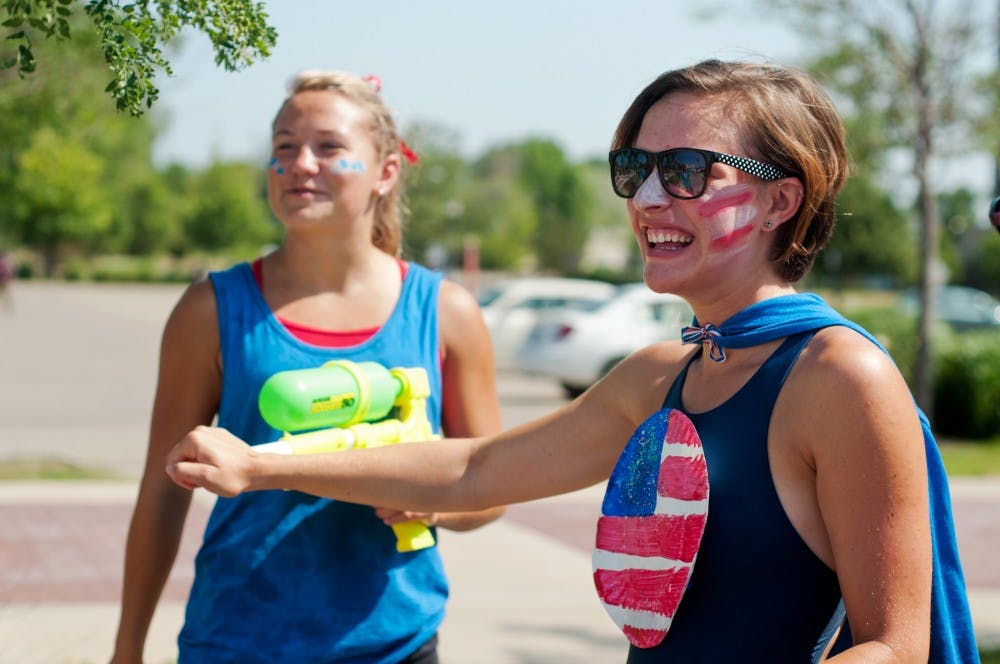 Mason resident Abi Combs, right, grabs Mason resident Emily Reader's squirt gun on July 4, 2012 during the Fourth of July parade in Lansing. The two cousins were members of a float regarding life-guarding. Julia Nagy/The State News