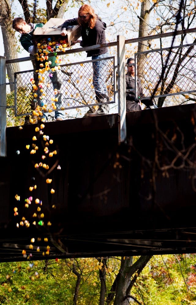 Mechanical engineering senior Jon Diclemente and prelaw sophomore Jamie Crist dump a box of over 600 rubber ducks into the Red Cedar River Saturday afternoon during the 2nd Annual Rubber Ducky Derby. The event was by Phi Sigma Pi held to raise money for Teach for America. Matt Hallowell/The State News