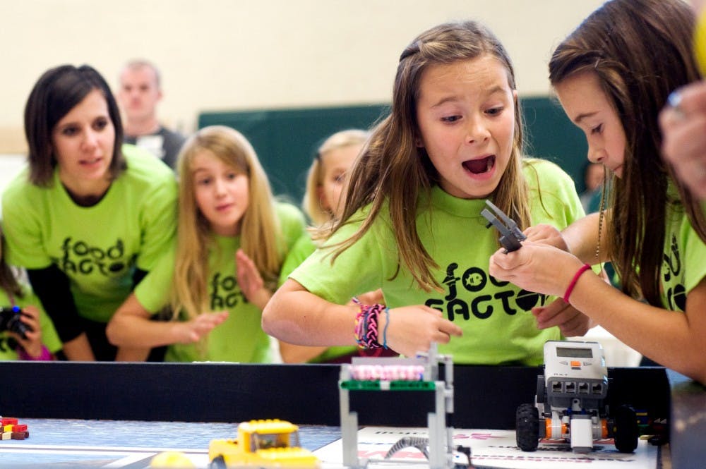 Molly Daily, 7, center left, cheers on her sister Megan, 10, far right, as the clock counts down the final seconds while they compete with their lego robot at the FIRST LEGO League regional competition at IM Circle on Saturday. Molly and Megan were competing for the Lego All-Stars from Carson City, Mich. Lauren Wood/The State News