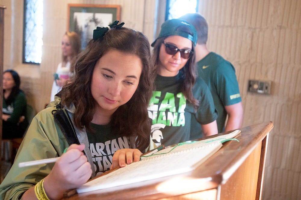 	<p>Communication senior Victoria Weber signs the visitor book while Marketing senior Alana Zaskowski waits for her turn, Oct. 12, 2013, at the Beaumont Tower. The tower is open everyTuesday at noon for visitors. Georgina De Moya/The State News</p>