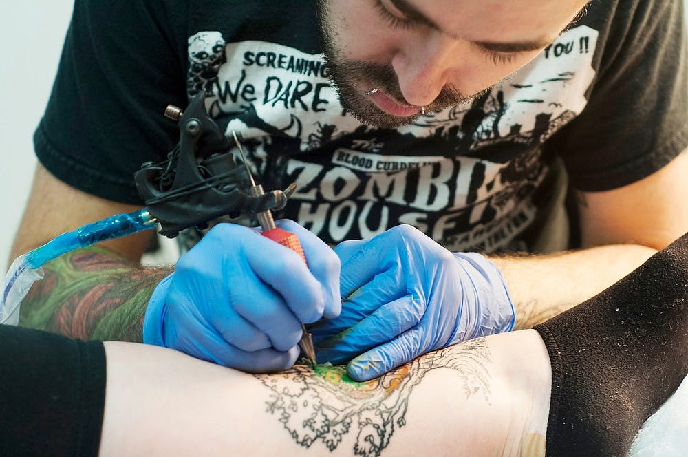 	<p>Lansing resident and tattoo artist Nate Kraus does a tree tattoo on Dimondale, Mich. resident Brianna Schafer Nov. 7, 2013, at Splash of Color. Kraus has done an average of at least 3,000 tattoos over the span of his 8 year career. Margaux Forster/The State News</p>