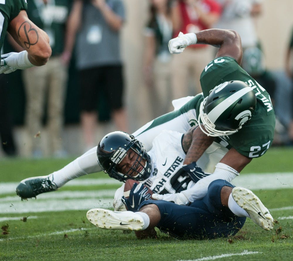 Senior defensive back Khari WIllis (27) attempts to strip the ball out of the receivers hand after making a tackle during the game against Utah State on Aug. 31, 2018 at Spartan Stadium. The Spartans defeated the Aggies 38-31.