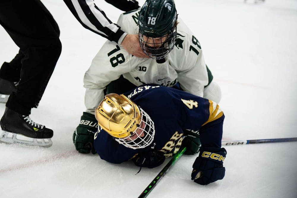 A referee attempts to pull Michigan State junior right wing Joey Larson (18) off of Notre Dame junior defenseman Michael Mastrodomenico (4) at Munn Ice Arena on March 15, 2025. The Spartans took a 1-0 victory over the Fighting Irish, advancing to the Big Ten Championship.