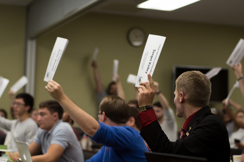 <p>ASMSU members raise their placards during an ASMSU meeting on Oct. 5, 2017 at Student Services. The meeting concluded by passing Bill 54-06 which aims to support sexual assault victims in the MSU community by a vote of 39-2-0.&nbsp;</p>