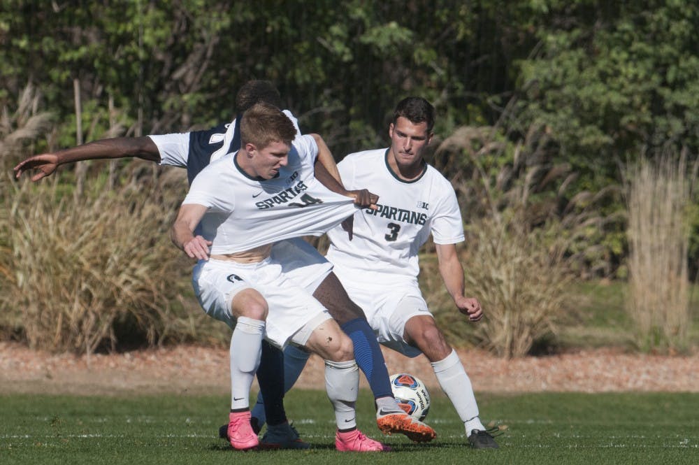 Senior defender Dewey Lewis (14) and junior defender Jimmy Fiscus (3) challenger junior forward Aymar Sigue (7) for the ball during the game against Penn State on Nov. 6, 2016 in DeMartin Stadium. The Spartans defeated the Nittany Lions, 2-1.